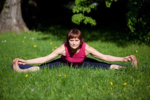 Kobieta na świeżym powietrzu na trawie ćwiczy jogę