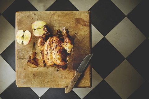 Pieczony kurczak na desce obok jabłko przekrojone na pół