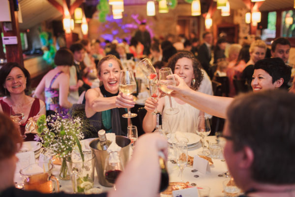 Goście weselni przy stole wznoszą toast w Folwarku Badowo