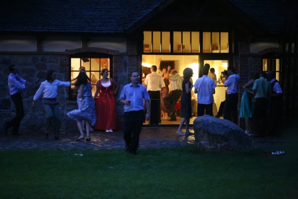 Goście weselni bawiący się wieczorem na zewnątrz w Folwarku badowo